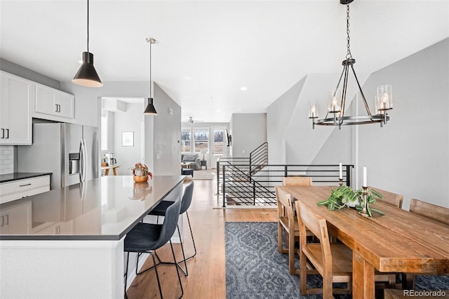 kitchen featuring white cabinets, stainless steel fridge, decorative backsplash, and pendant lighting