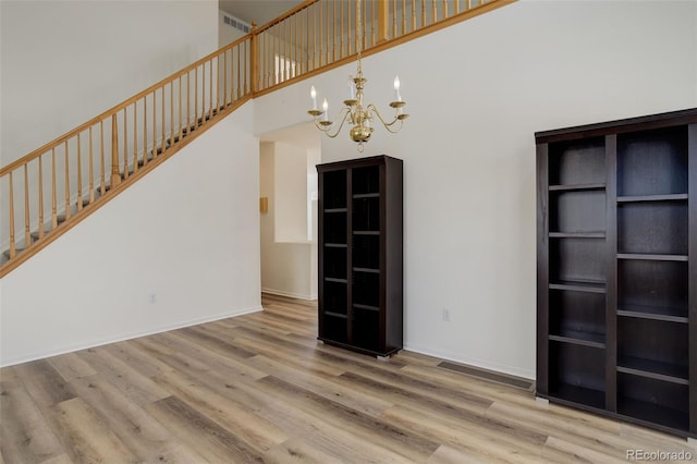 21968 E Princeton Dr, Aurora, CO 80018 - unfurnished living room featuring a chandelier, wood finished floors, a towering ceiling, baseboards, and stairway