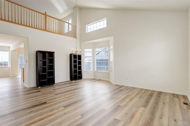 21968 E Princeton Dr, Aurora, CO 80018 - unfurnished living room with a chandelier, light wood finished floors, healthy amount of natural light, and high vaulted ceiling