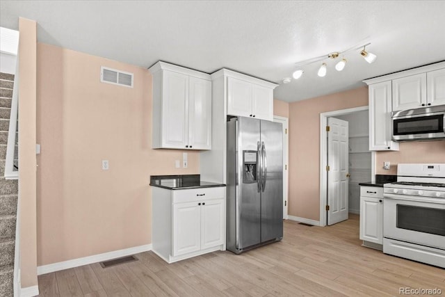 kitchen with appliances with stainless steel finishes, dark countertops, and visible vents