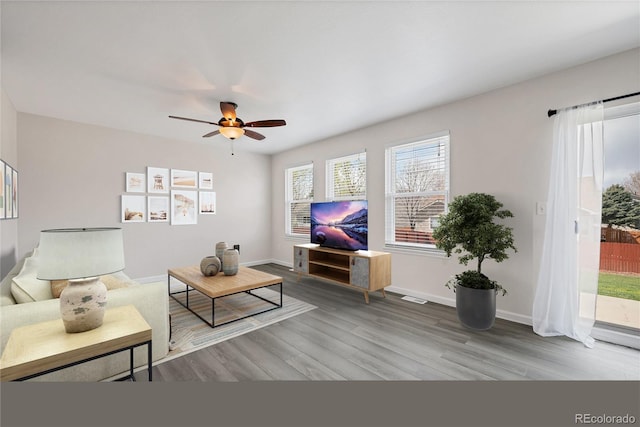 living area featuring baseboards, ceiling fan, wood finished floors, and visible vents