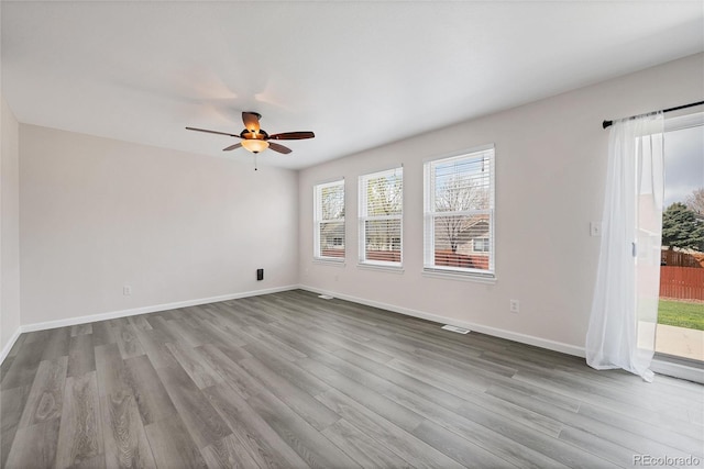 empty room with visible vents, baseboards, ceiling fan, and wood finished floors
