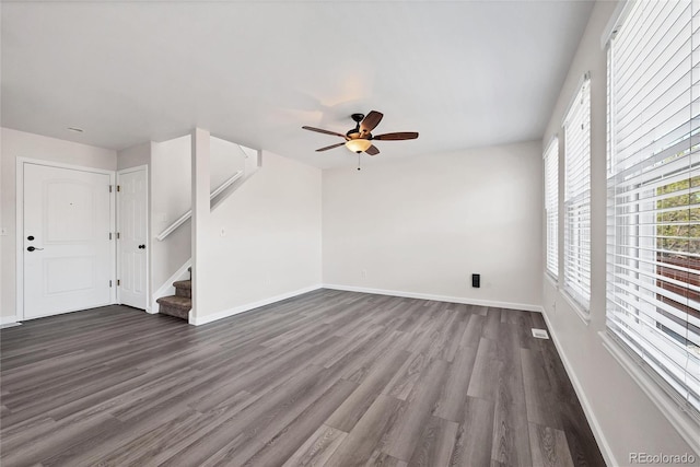 unfurnished living room with baseboards, a ceiling fan, dark wood finished floors, and stairway