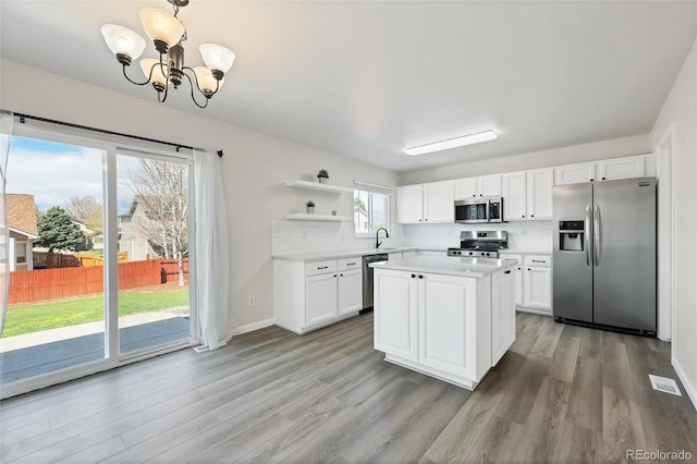 kitchen featuring open shelves, light wood finished floors, appliances with stainless steel finishes, and light countertops
