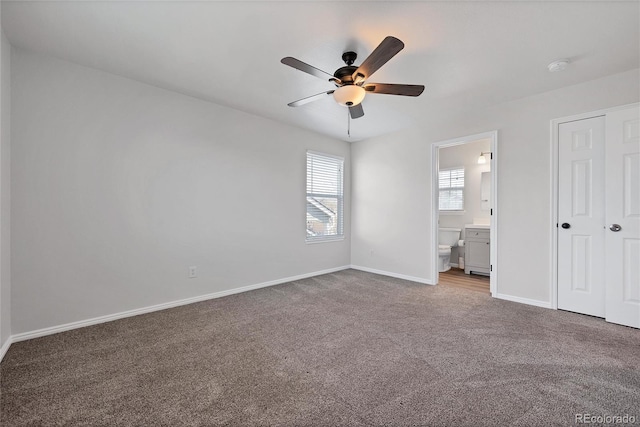 unfurnished bedroom featuring baseboards, connected bathroom, carpet, and ceiling fan