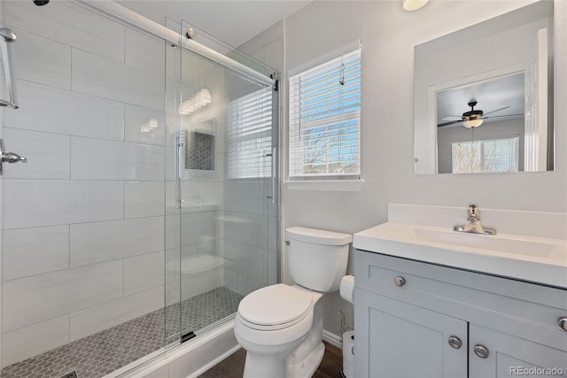 bathroom with ceiling fan, a shower stall, wood finished floors, vanity, and toilet