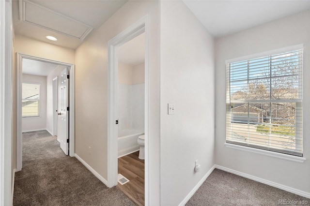 hallway with dark colored carpet, baseboards, and visible vents