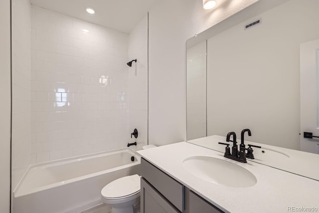 full bathroom featuring vanity, tiled shower / bath combo, and toilet