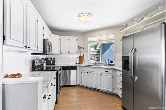 kitchen with white cabinetry, light hardwood / wood-style flooring, backsplash, appliances with stainless steel finishes, and sink