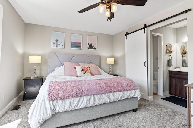 bedroom with light carpet, ensuite bathroom, ceiling fan, and a barn door