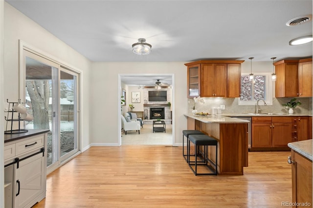 3190 Ward Ct, Wheat Ridge, CO 80215 - kitchen featuring a kitchen breakfast bar, brown cabinets, light wood-style flooring, and decorative backsplash