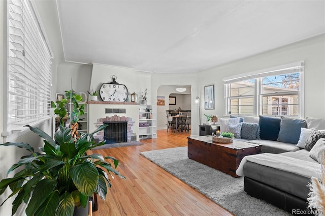 living room with a brick fireplace and hardwood / wood-style flooring