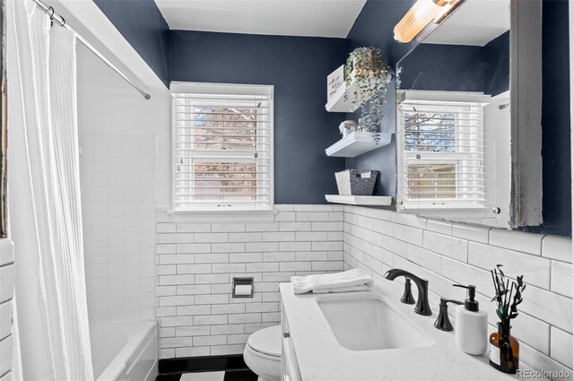 full bathroom featuring plenty of natural light, tile walls, shower / tub combo, and toilet