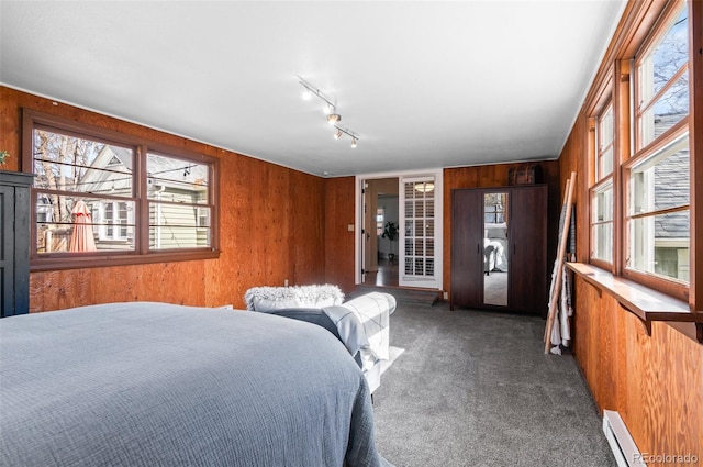 carpeted bedroom with a baseboard radiator and wood walls