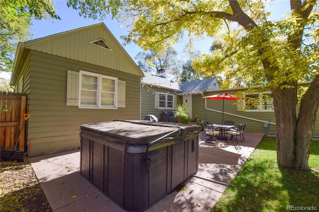 rear view of property with a hot tub and a patio