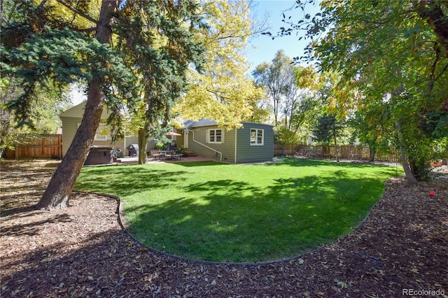 view of yard featuring a hot tub, an outdoor structure, and a patio area