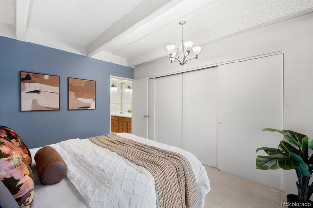 bedroom featuring carpet floors, a closet, a notable chandelier, ensuite bathroom, and beamed ceiling