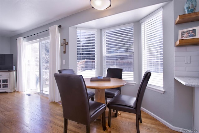 dining space featuring light wood finished floors and baseboards