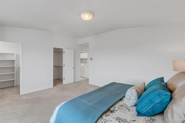 bedroom with carpet flooring, vaulted ceiling, a spacious closet, and washer / clothes dryer