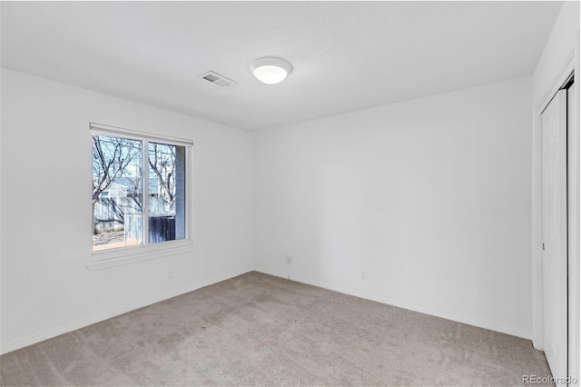 carpeted spare room featuring baseboards and visible vents