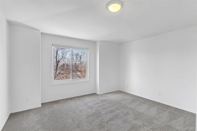 carpeted empty room featuring baseboards and visible vents