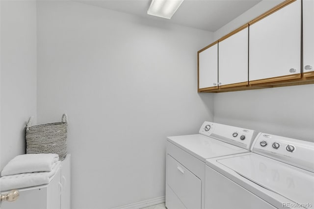 clothes washing area with cabinet space, washing machine and clothes dryer, and baseboards
