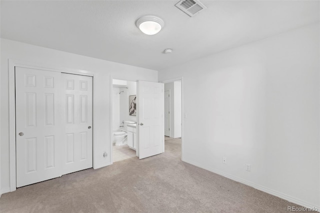 unfurnished bedroom featuring a closet, carpet, baseboards, ensuite bath, and visible vents