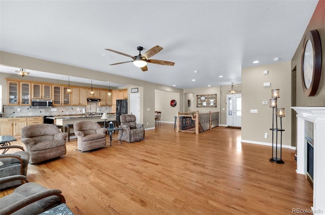 living room with ceiling fan, sink, and light hardwood / wood-style floors