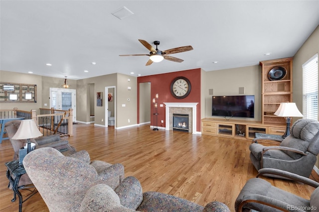 living room with a fireplace, light hardwood / wood-style floors, and ceiling fan