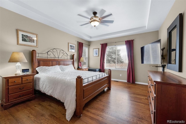 bedroom featuring ceiling fan, dark hardwood / wood-style floors, and a raised ceiling