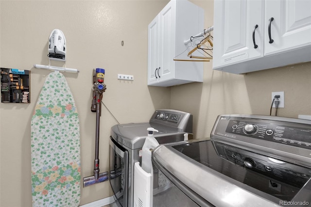 laundry room with washing machine and clothes dryer and cabinets