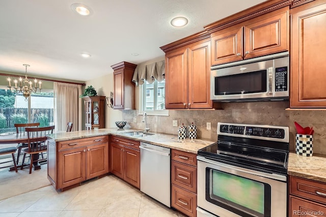 3544 Dyanna Dr, Thornton, CO 80241 - kitchen featuring stainless steel appliances, a chandelier, brown cabinets, light stone countertops, and recessed lighting