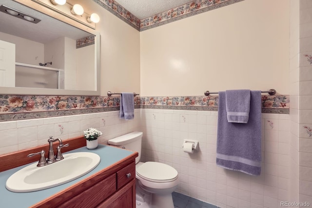 3544 Dyanna Dr, Thornton, CO 80241 - full bath featuring a wainscoted wall, a stall shower, tile walls, vanity, and a textured ceiling
