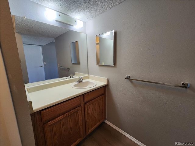 14499 E 1st Dr Unit A05, Aurora, CO 80011 - bathroom featuring a textured ceiling, vanity, wood finished floors, baseboards, and a textured wall