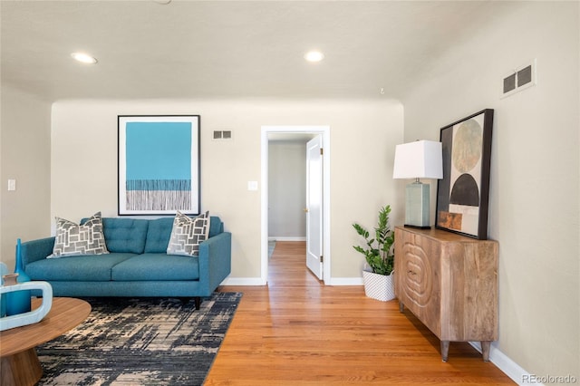 living room featuring light wood-style floors, visible vents, and baseboards