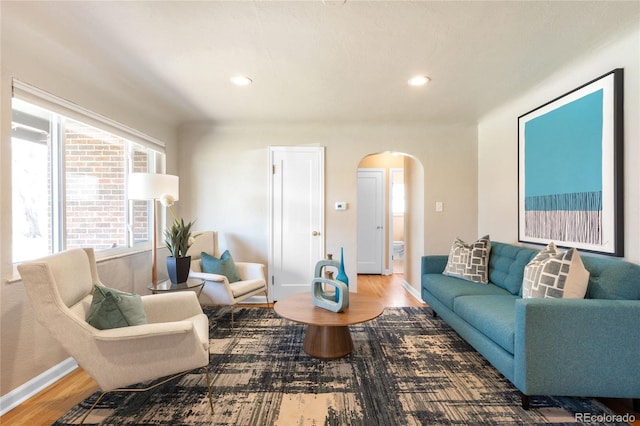 living area featuring recessed lighting, baseboards, arched walkways, and wood finished floors