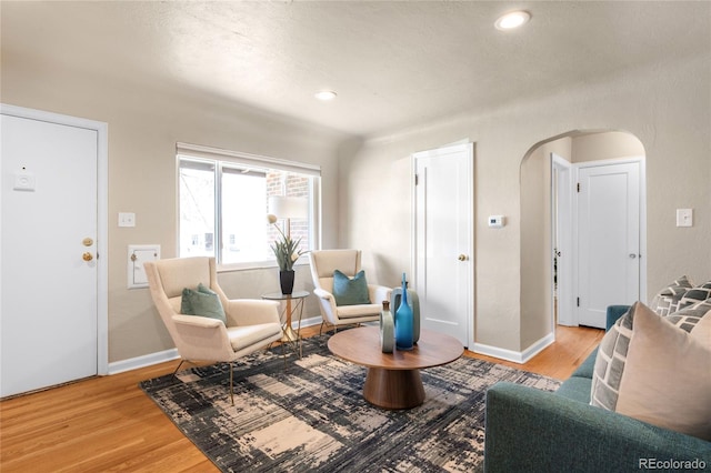 sitting room with recessed lighting, baseboards, arched walkways, and wood finished floors