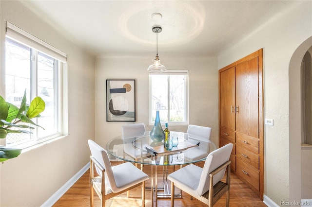 dining area with arched walkways, baseboards, and a wealth of natural light