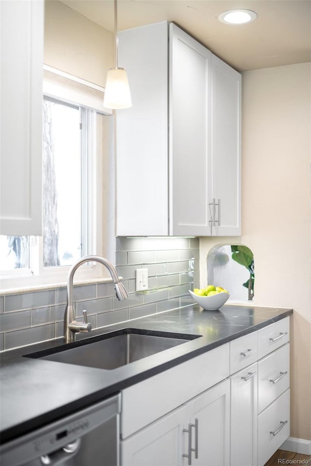 kitchen with a sink, tasteful backsplash, dishwasher, and white cabinetry