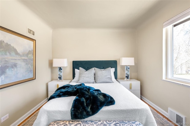 bedroom with visible vents, baseboards, and wood finished floors