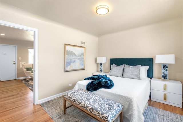 bedroom with visible vents, baseboards, and wood finished floors