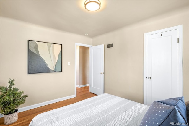 bedroom with visible vents, baseboards, and wood finished floors