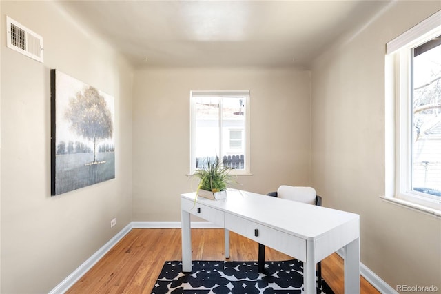 office featuring light wood finished floors, visible vents, plenty of natural light, and baseboards