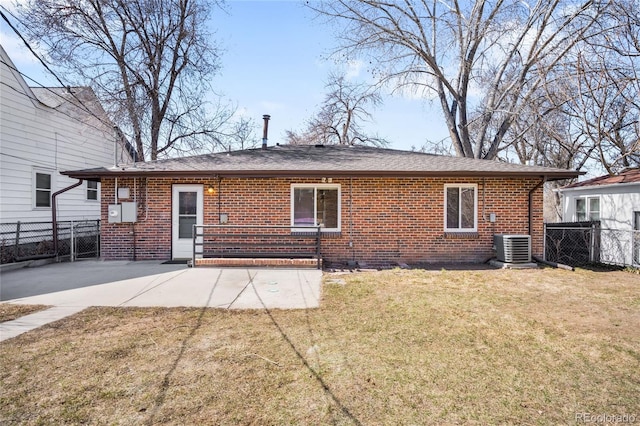 rear view of property with a yard, fence, and brick siding