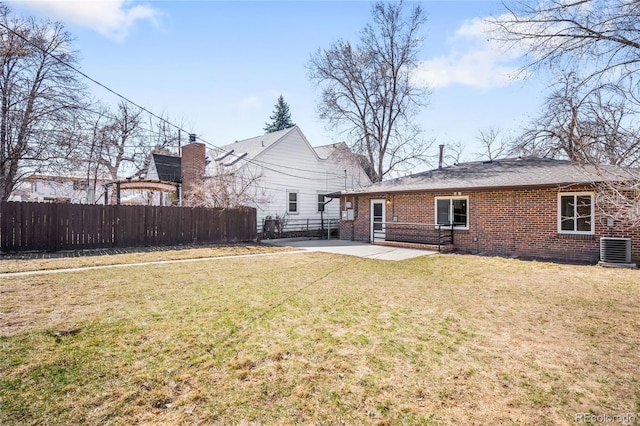 rear view of house with fence, a yard, central air condition unit, a patio area, and brick siding