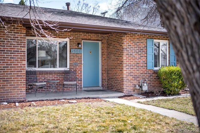 property entrance with brick siding and roof with shingles