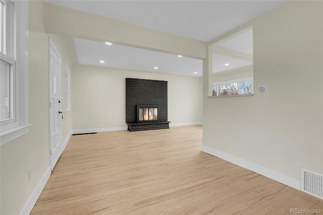 unfurnished living room featuring light hardwood / wood-style floors and a brick fireplace