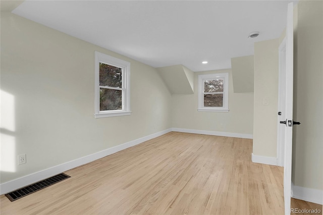 additional living space featuring light wood-type flooring and vaulted ceiling