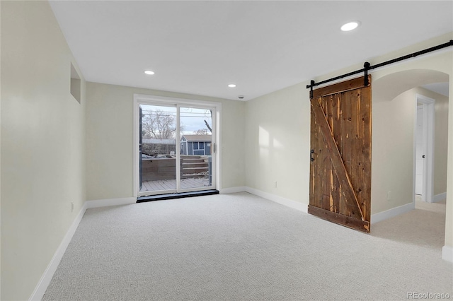 empty room featuring a barn door and light colored carpet