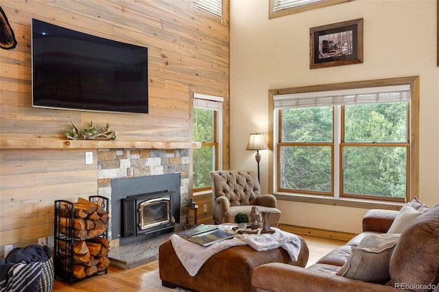 living room with wood walls, light hardwood / wood-style flooring, a wood stove, and a fireplace